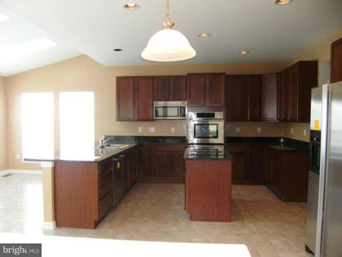 64 Mineral Springs Road Ranson, WV 25438 - Photo 3 of 12 a kitchen with kitchen island granite countertop wooden cabinets and stainless steel appliances