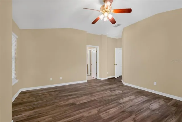 a view of an empty room with window and wooden floor
