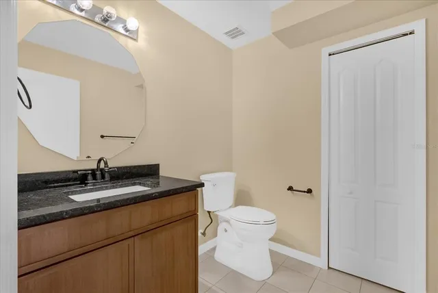 a bathroom with a granite countertop sink toilet and mirror