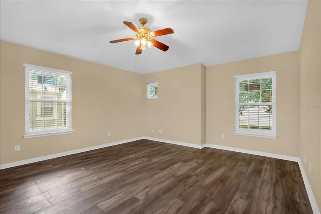 a view of an empty room with wooden floor and a window