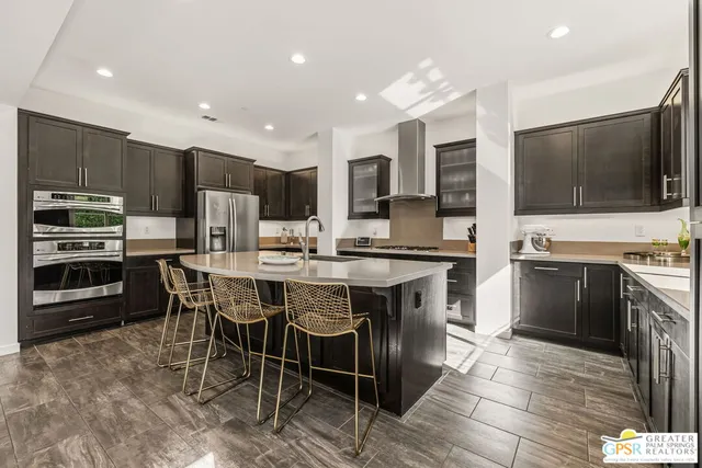 a dining hall with stainless steel appliances kitchen island granite countertop a refrigerator and a sink