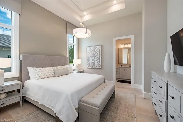 a spacious bedroom with a bed and a flat tv screen on dresser