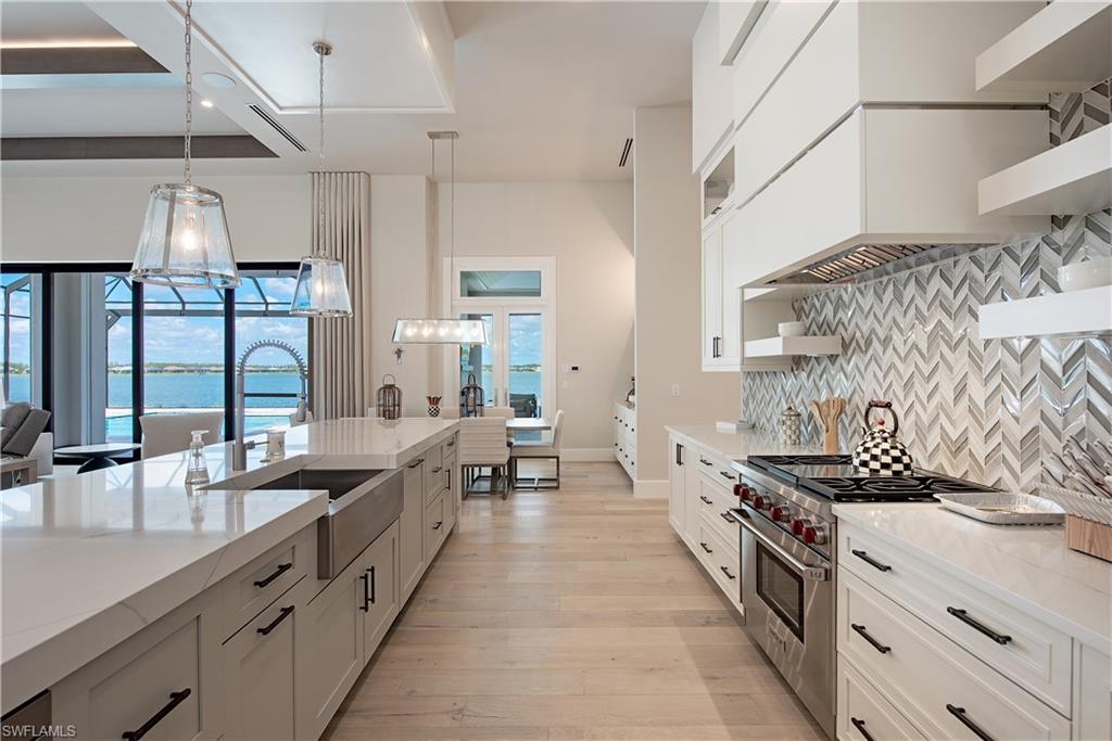 18354 Blue Eye Loop Fort Myers, FL 33913 - Photo 4 of 27 a large kitchen with stainless steel appliances a sink dishwasher a stove and a dining table with the view of living room