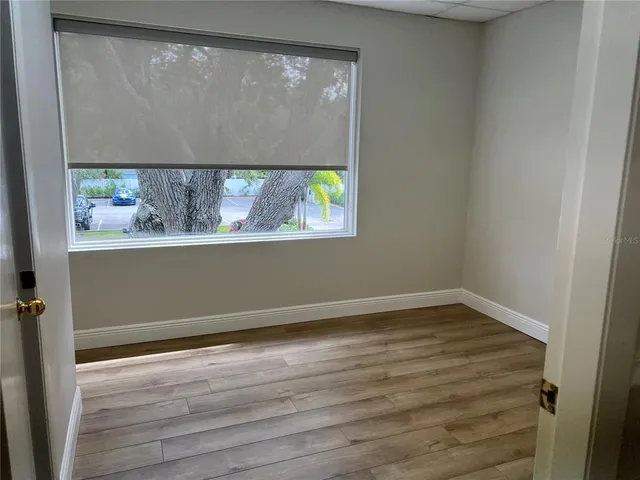 a view of an empty room with wooden floor and a window