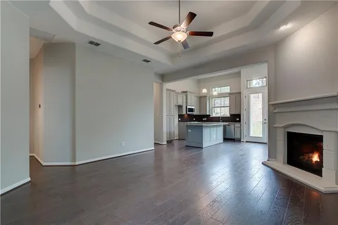 a view of an empty room with a fireplace and a ceiling fan