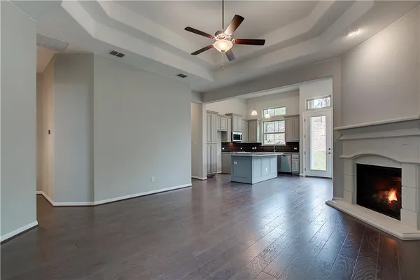 a view of an empty room with a fireplace and a ceiling fan