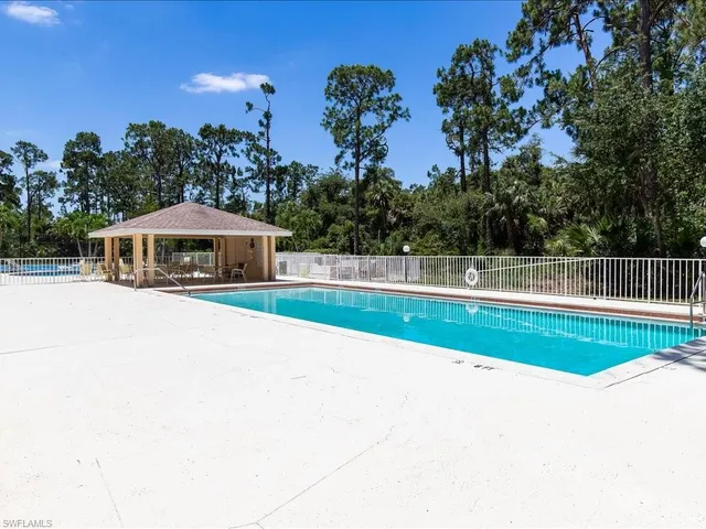 a view of house with swimming pool outdoor seating and trees
