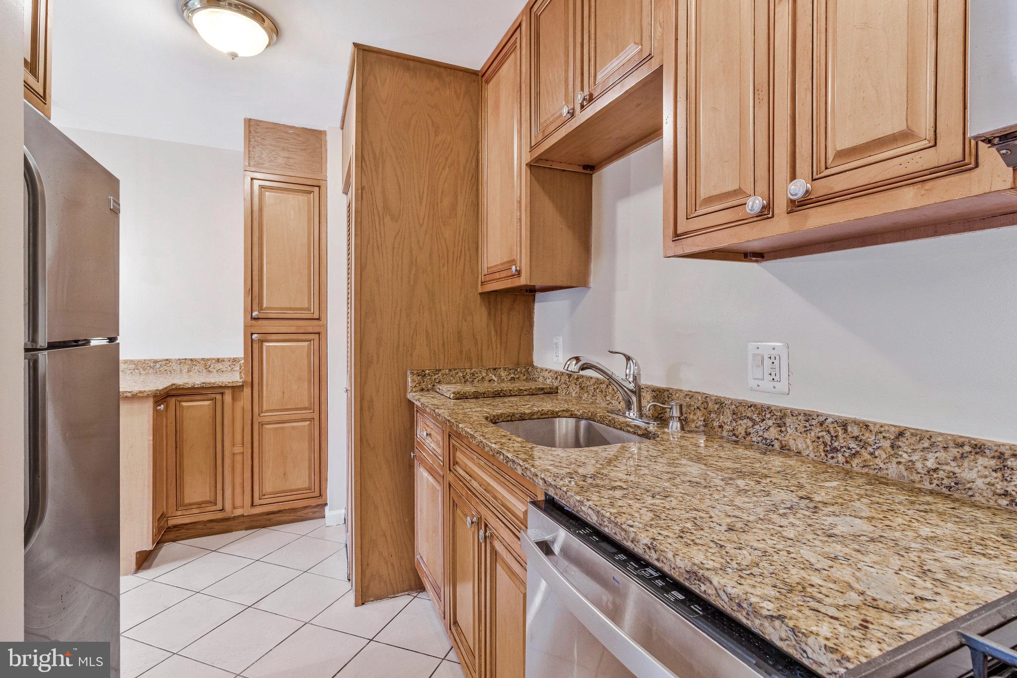 3802 Bel Pre Road, Unit 38025 Silver Spring, MD 20906 - Photo 18 of 36 a kitchen with granite countertop a sink and a refrigerator
