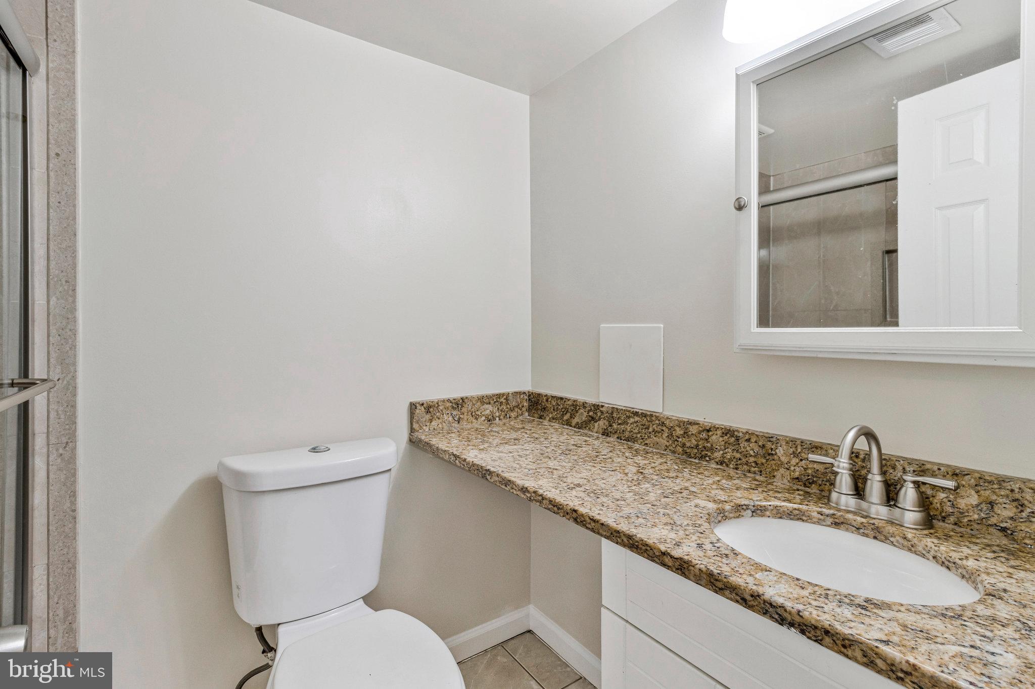 3802 Bel Pre Road, Unit 38025 Silver Spring, MD 20906 - Photo 23 of 36 a bathroom with a granite countertop toilet sink and mirror