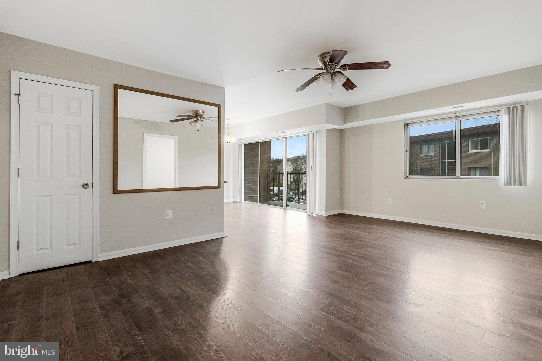 3802 Bel Pre Road, Unit 38025 Silver Spring, MD 20906 - Photo 3 of 36 a view of a big room with wooden floor a ceiling fan and windows