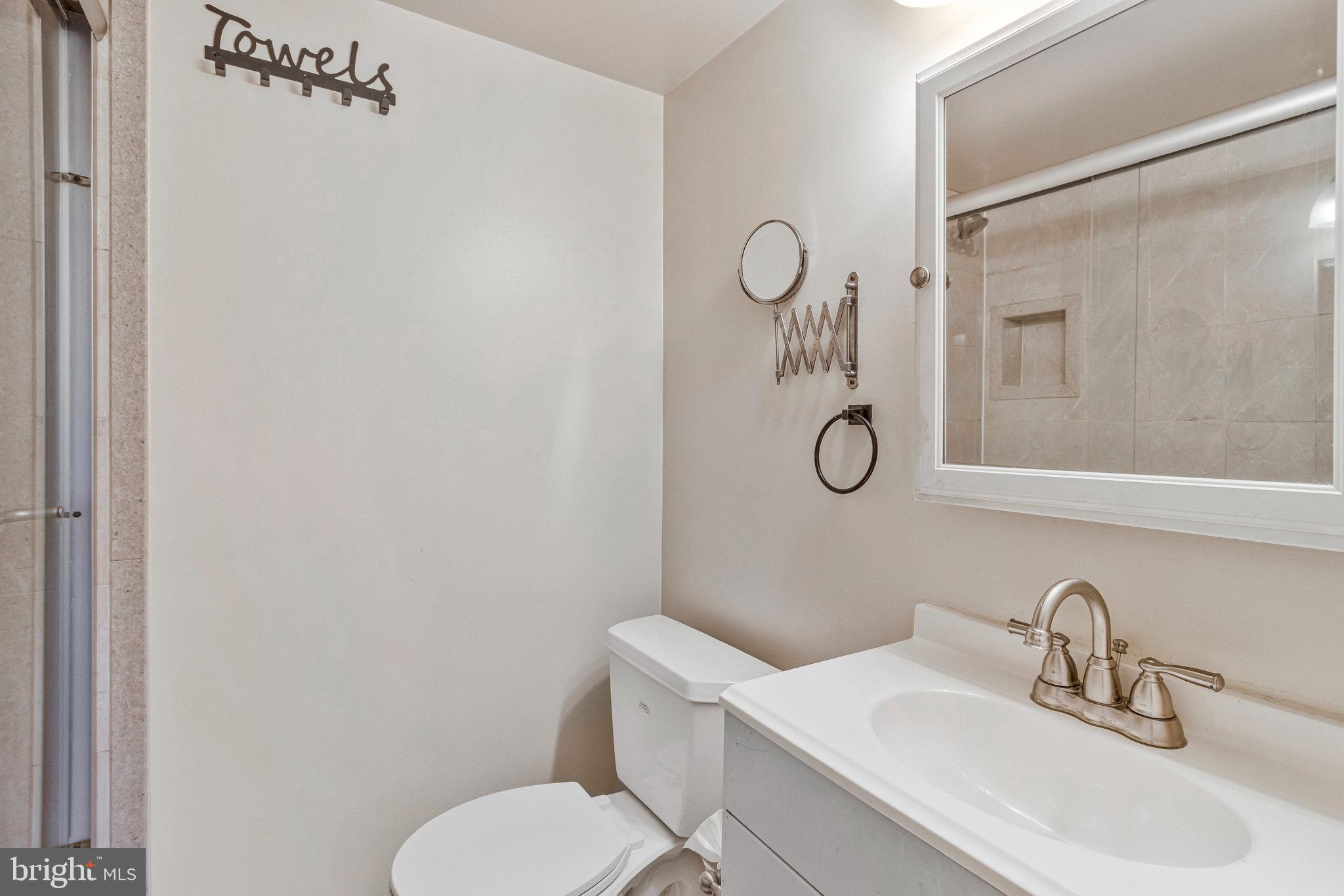 3802 Bel Pre Road, Unit 38025 Silver Spring, MD 20906 - Photo 32 of 36 a bathroom with a toilet sink vanity and mirror