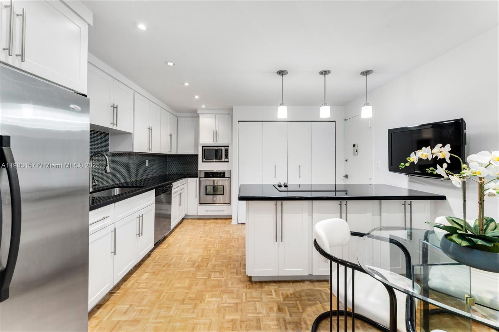 10155 Collins Avenue, Unit 307 Bal Harbour, FL 33154 - Photo 5 of 18 a kitchen with kitchen island granite countertop a white cabinets and wooden floor