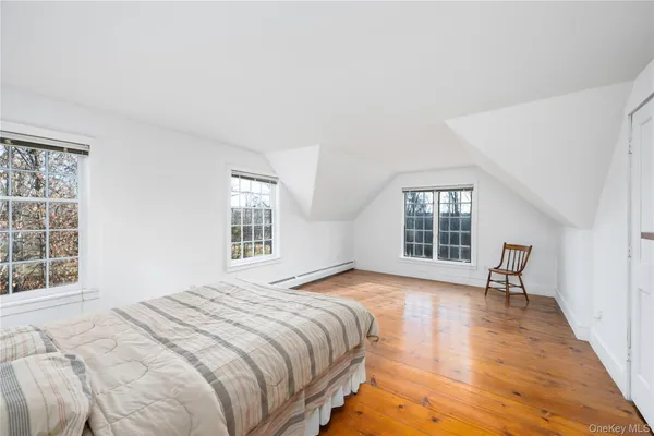 a bedroom with a bed windows and wooden floor