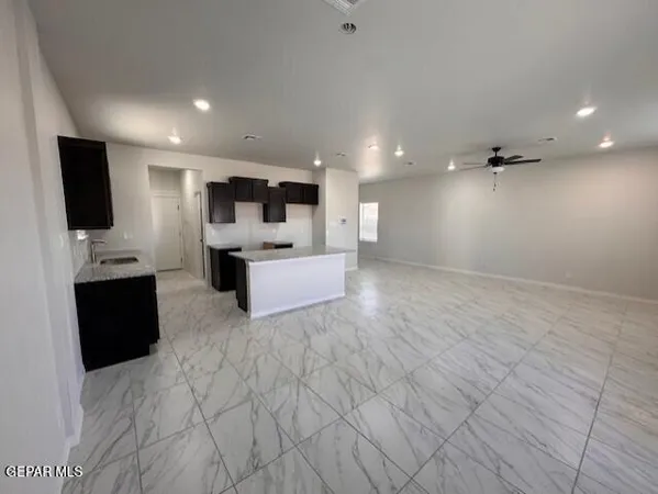 a living room with stainless steel appliances kitchen island granite countertop a sink and a black cabinets