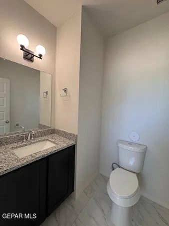 a bathroom with a granite countertop toilet sink and mirror