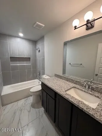 a bathroom with a granite countertop bathtub sink vanity and toilet