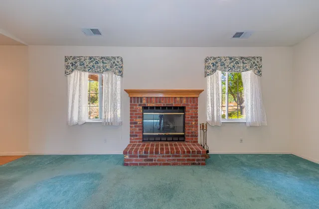 an empty room with windows and fireplace