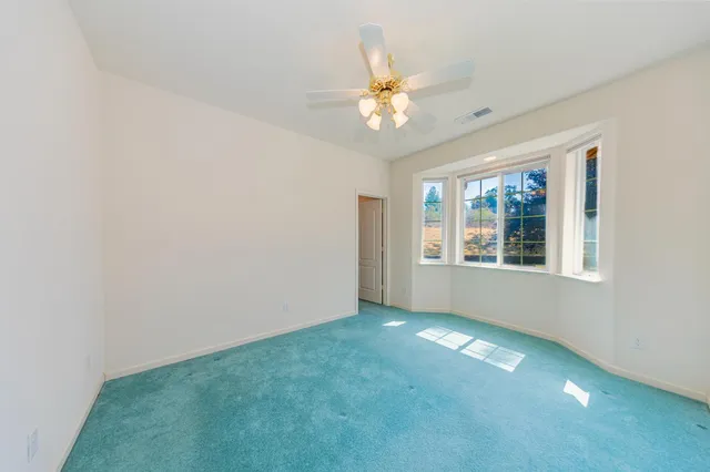 a view of an empty room with window and chandelier fan