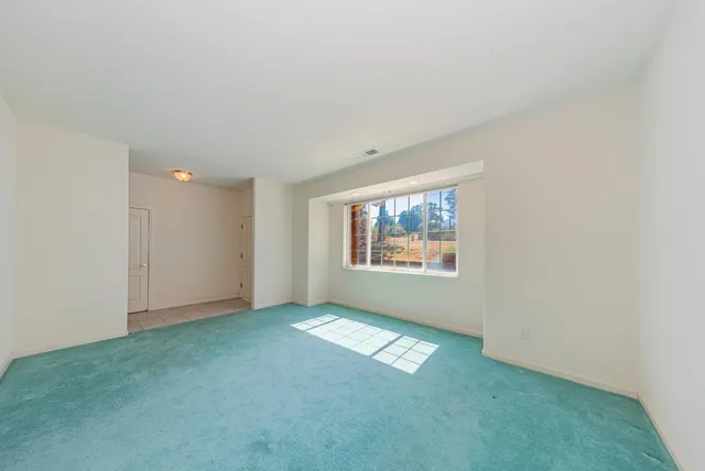 a view of an empty room and a kitchen