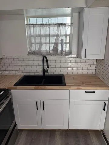 a kitchen with white cabinets and sink