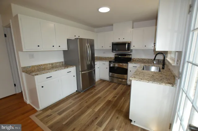 a kitchen with granite countertop a refrigerator stove and sink