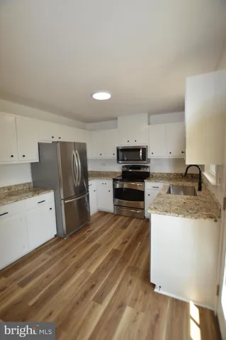 a kitchen with a refrigerator a stove top oven a sink and cabinets