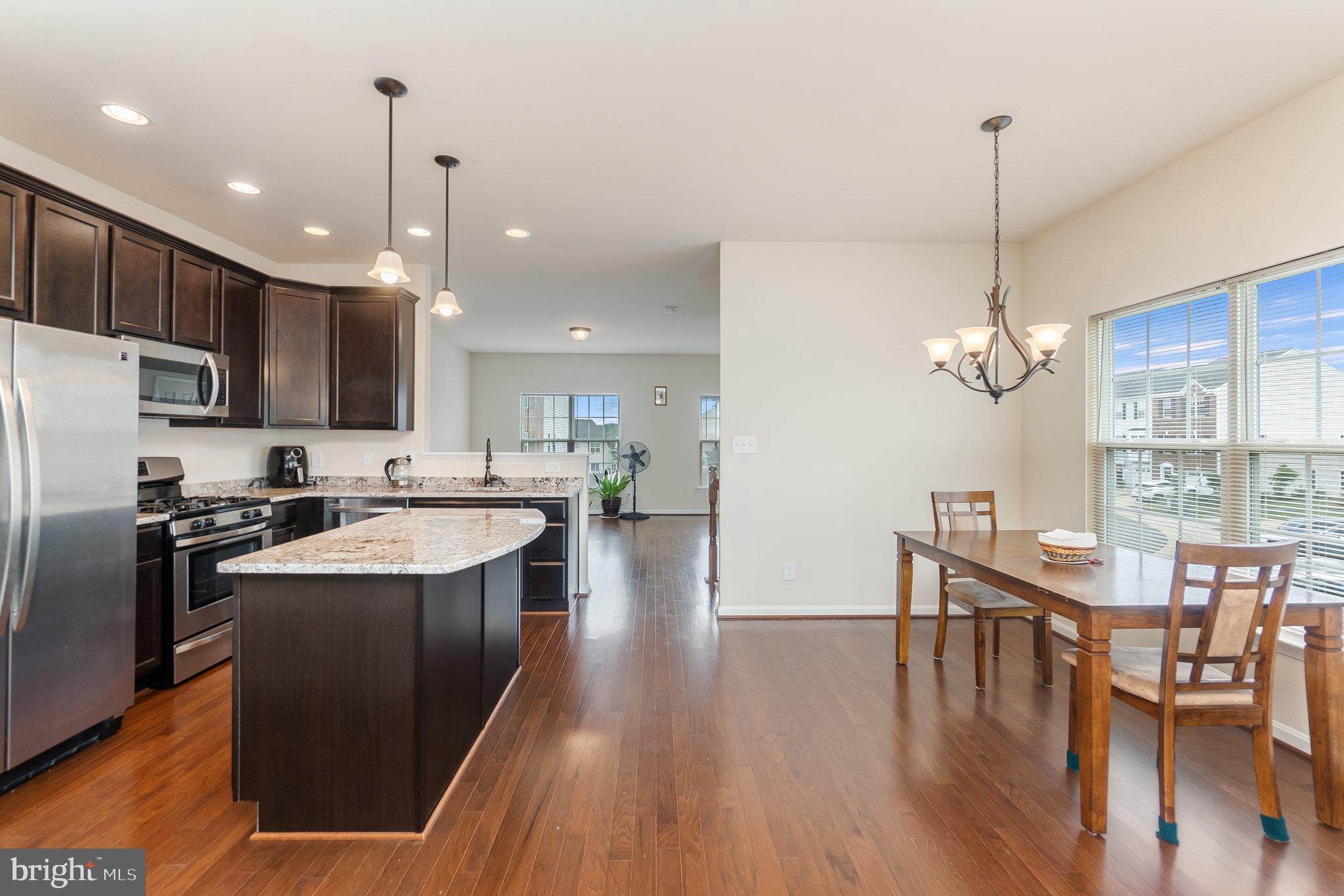 4711 Wensel Road Fredericksburg, VA 22408 - Photo 11 of 33 a kitchen with stainless steel appliances kitchen island granite countertop a stove a refrigerator a kitchen island a dining table and chairs with wooden floor