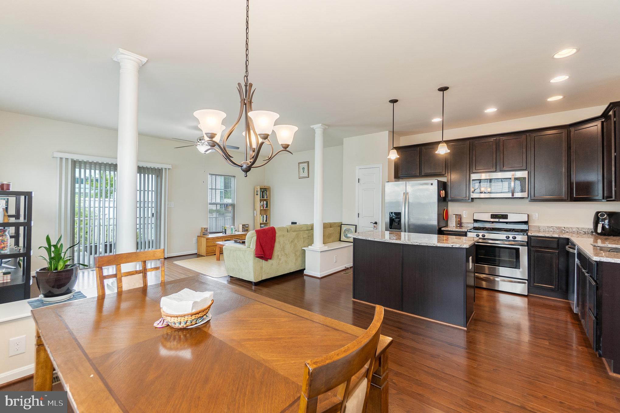 4711 Wensel Road Fredericksburg, VA 22408 - Photo 7 of 33 a kitchen with stainless steel appliances kitchen island granite countertop a sink a stove a dining table and chairs with wooden floor