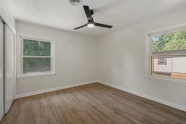 a view of empty room with wooden floor and fan