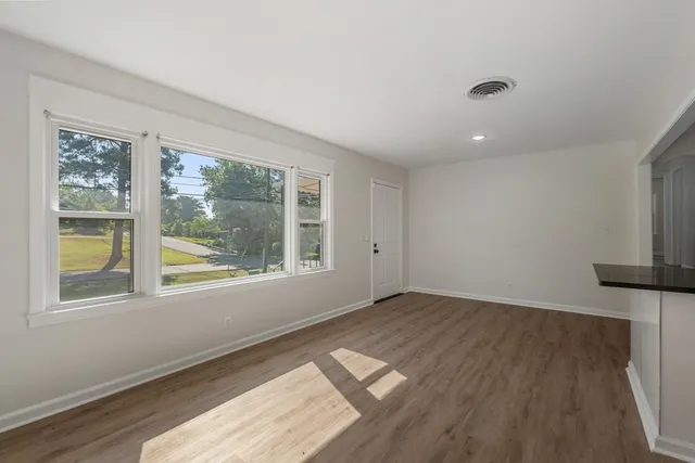 a view of an empty room with a window and wooden floor