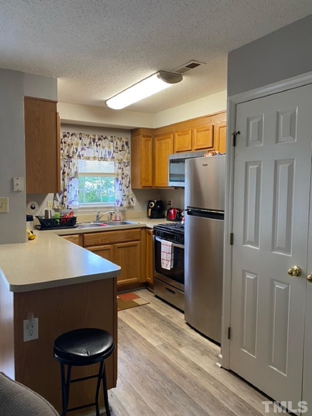 141 Jones Franklin Road, Unit H Raleigh, NC 27606 - Photo 14 of 36 a kitchen with stainless steel appliances a refrigerator a sink a stove a table and chairs