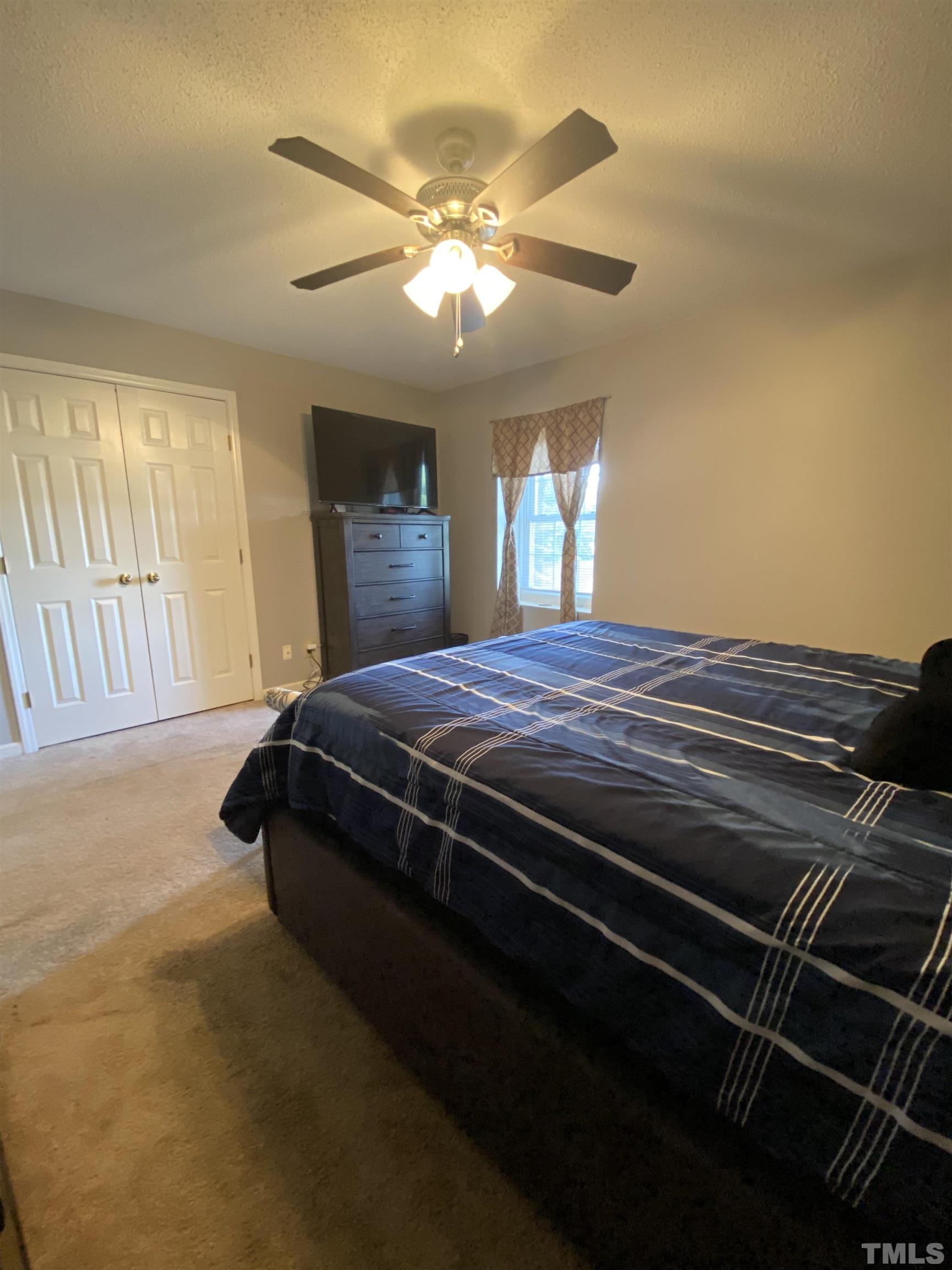 141 Jones Franklin Road, Unit H Raleigh, NC 27606 - Photo 23 of 36 a bed sitting in a bedroom next to a window and a chandelier