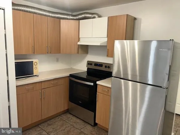 a kitchen with stainless steel appliances a refrigerator a sink a stove and white cabinets