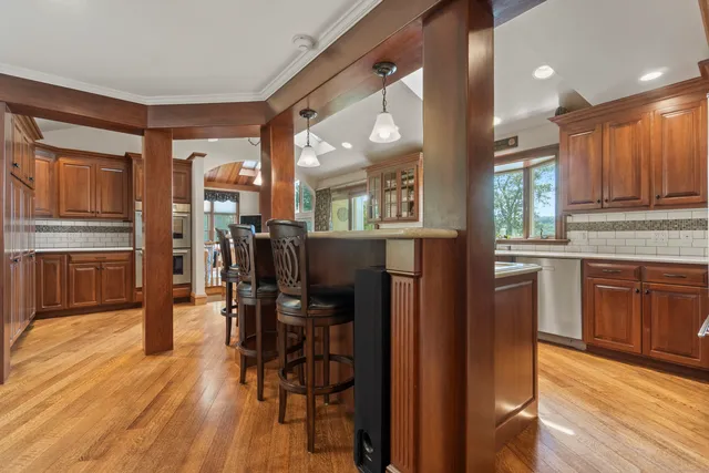 a kitchen with stainless steel appliances kitchen island granite countertop a refrigerator a stove a sink a dining table and chairs with wooden floor