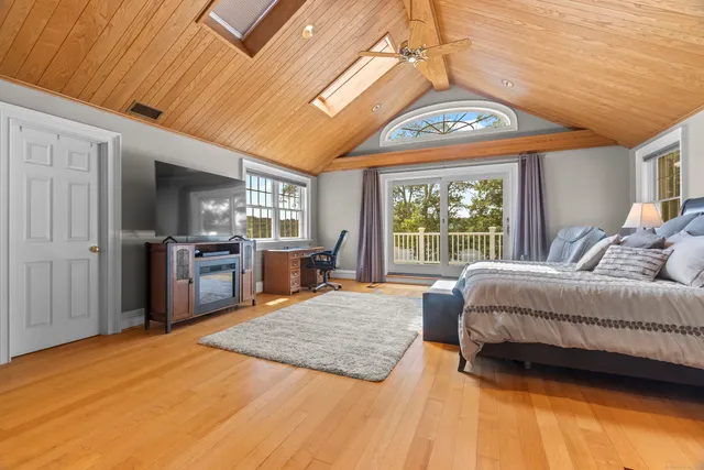 a spacious bedroom with a large bed a chandelier and windows