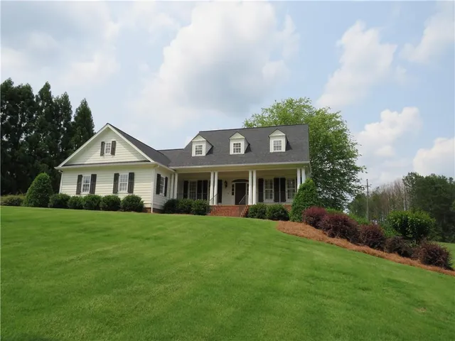 a view of a house with a big yard and large trees