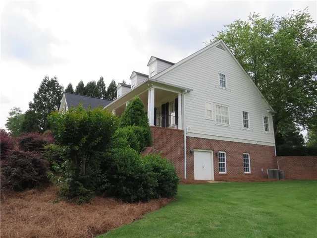 a view of a yard in front of a house with plants and large tree