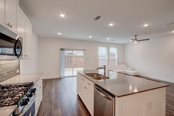 a kitchen with stainless steel appliances granite countertop a sink a stove and a wooden floors