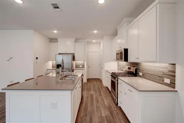a kitchen with granite countertop a sink stove cabinets and refrigerator