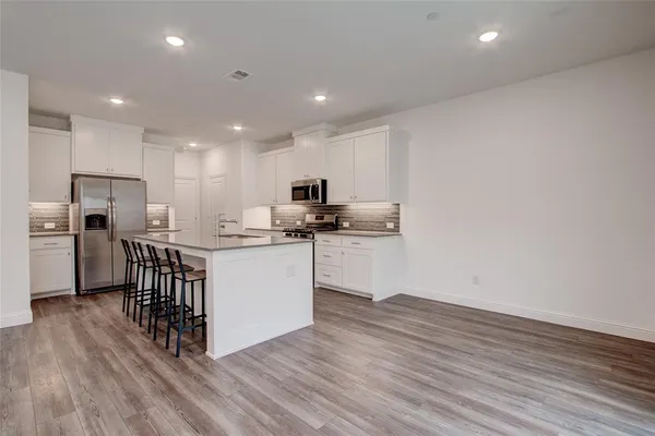 a kitchen with a sink wooden floor and white cabinets