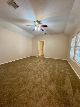 an empty room with windows and fan
