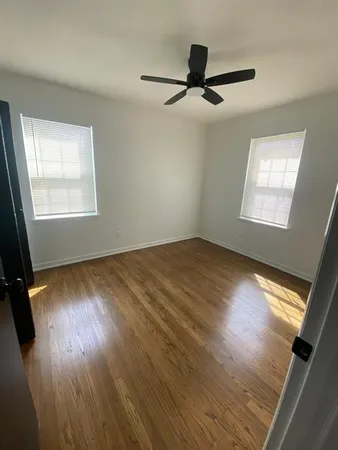 a view of empty room with wooden floor and fan