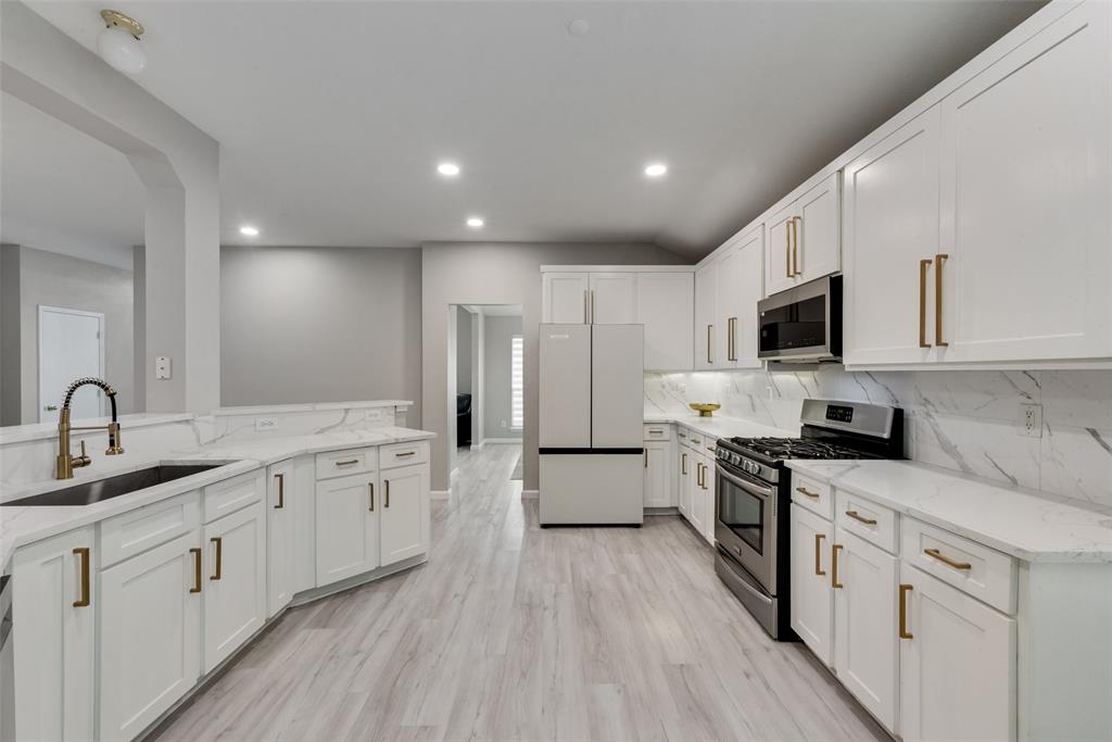 506 Pecos Path Drive Murphy, TX 75094 - Photo 8 of 19 a large kitchen with stainless steel appliances granite countertop a stove top oven a sink a refrigerator and white cabinets with wooden floor
