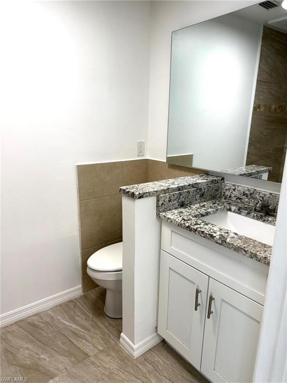 585 14th Street North Naples, FL 34102 - Photo 16 of 24 a bathroom with a granite countertop toilet and a sink