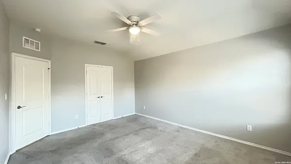 an empty room with a ceiling fan and a window