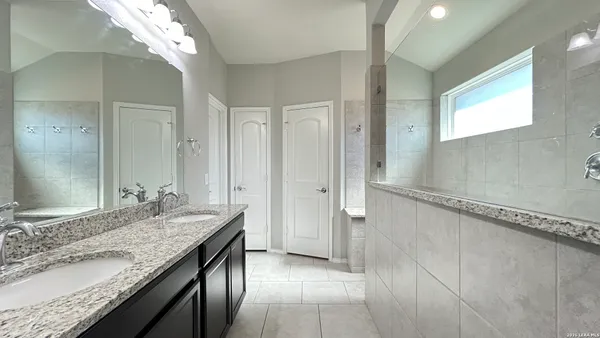 a bathroom with a granite countertop sink a mirror and a shower