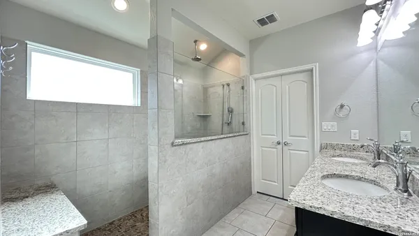 a bathroom with a granite countertop sink and a shower