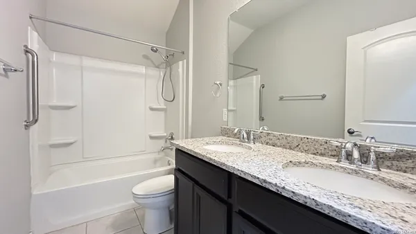 a bathroom with a granite countertop sink a toilet a shower and a mirror