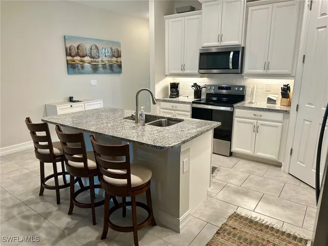 a kitchen with stainless steel appliances granite countertop a sink a stove a kitchen island and chairs