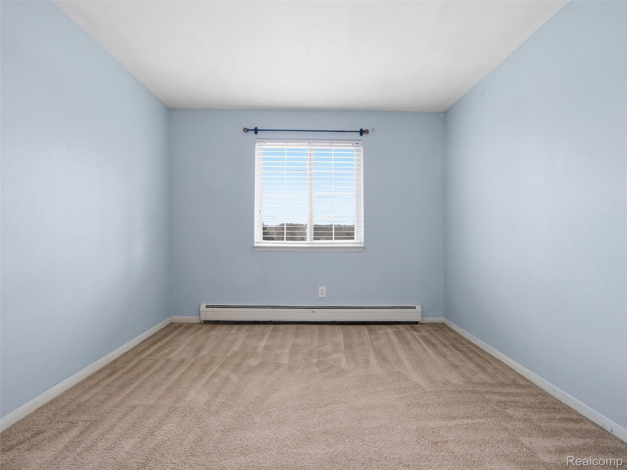 475 Baldwin Avenue, Unit 26 Rochester, MI 48307 - Photo 15 of 19 Unfurnished room featuring light colored carpet and a baseboard heating unit